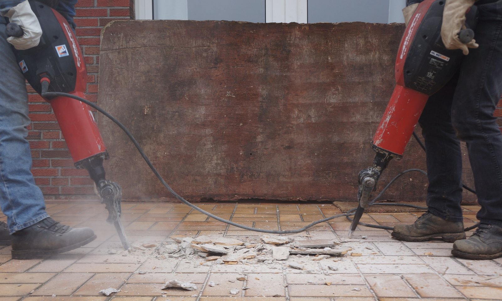 Twee werknemers die een vloer slopen met pneumatische hamers.