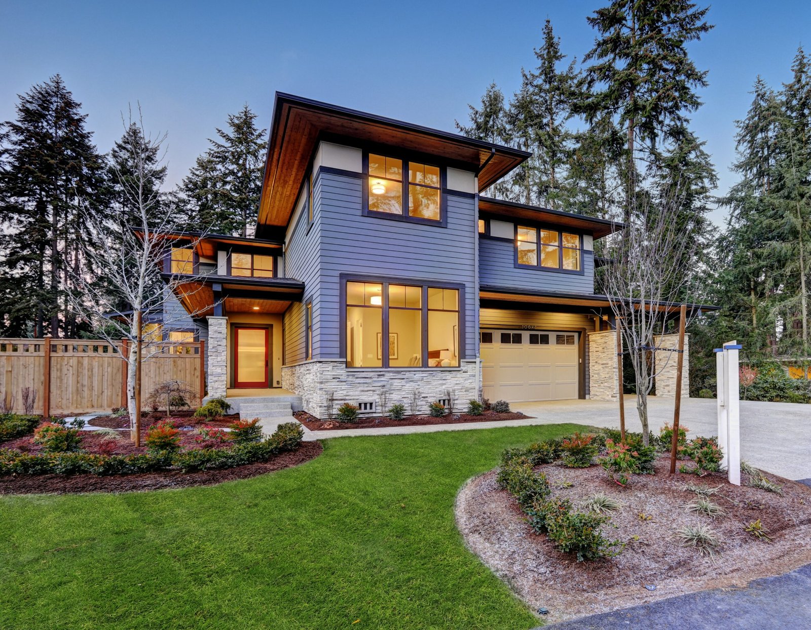 Moderne woning met blauw exterieur, grote ramen, en aangelegde tuin.